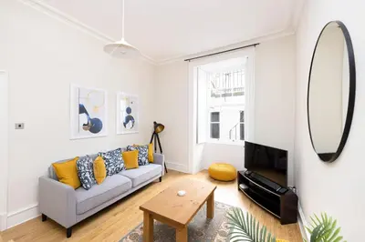 a living room with a couch and a mirror at JOIVY Chic Apartment near Stockbridge Market in Edinburgh