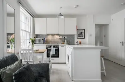a kitchen with white cabinets and a table and a couch at Edinburgh Castle Apartment G1 in Edinburgh