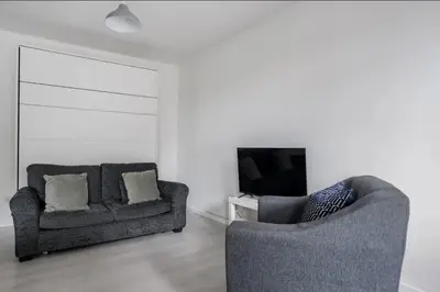 a living room with two chairs and a television at Edinburgh Castle Apartment G1 in Edinburgh