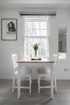 a white dining room table with white chairs and a window at Edinburgh Castle Apartment G1 in Edinburgh