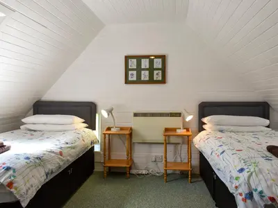 a attic room with two beds and two night stands at Burnside Cottage in Sliddery