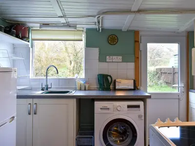 a kitchen with a washing machine and a sink at Burnside Cottage in Sliddery
