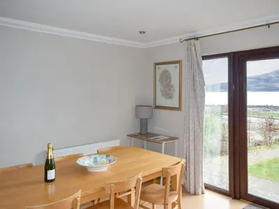 a dining room with a table and a large window at Rivendell in Lamlash
