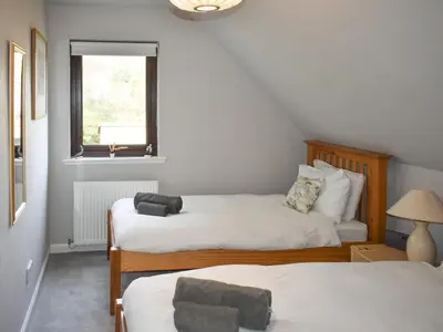 a bedroom with two beds and a window at Rivendell in Lamlash