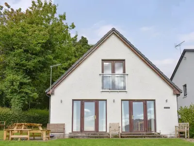 a white house with windows and a picnic table at Rivendell in Lamlash