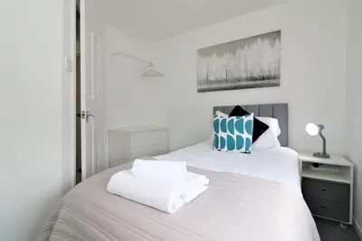 a bedroom with a white bed with towels on it at Signature - Barons Court in Paisley