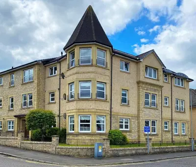 a large brick building with a pointed roof at NEW Super 2 Bedroom Flat in Falkirk in Falkirk
