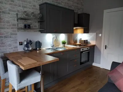a kitchen with black cabinets and a wooden counter top at On Yer Bike & Gone Fishin in Millport