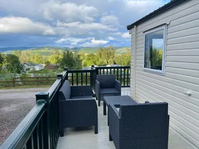a deck with chairs and tables on a house at Beautiful 3BR Holiday Home in Stunning Location - Pass the Keys in Moffat