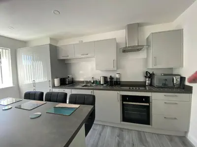 a kitchen with white cabinets and a table with chairs at Beautiful Riverside Holiday Home in Callander