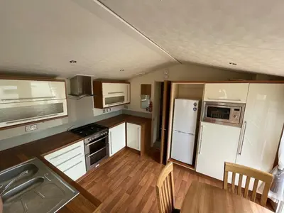 a small kitchen with white appliances and wooden floors at 2-Bedroom Caravan Located in Uddingston, Glasgow at Maryville Caravan Site in Uddingston