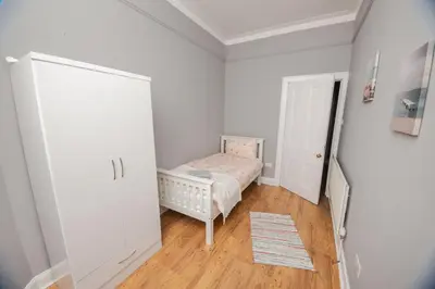 a small room with a crib and a small bedroom at Bonhill Getaway in Dumbarton
