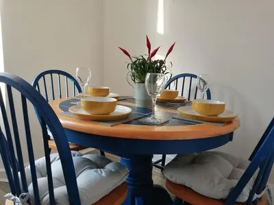 a dining room table with chairs and a blue table with dishes at Spacious stylish centraly located flat near beach in Largs