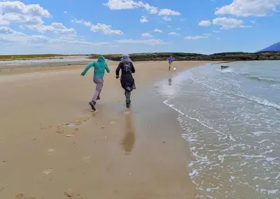 two people are walking on the beach at Loch Shuna Lodges in Craobh Haven