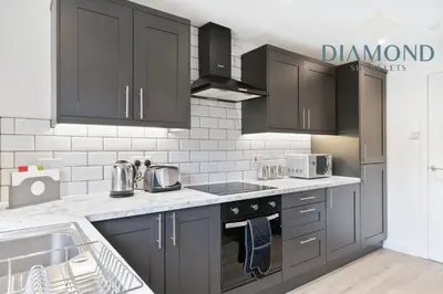 a kitchen with black cabinets and a sink at Grangemouth, 3 Bed House, Free Parking, Business or Leisure in Grangemouth