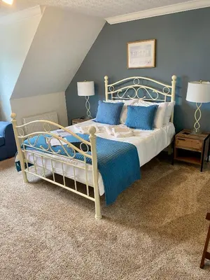 a bedroom with a white bed with blue pillows at Rowan House B&B Rooms & A Self Catering Apartment in Lochgoilhead