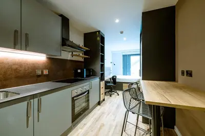 a kitchen with white cabinets and a wooden counter top at Modern Studio Apartments at Murieston Crescent in Edinburgh in Edinburgh