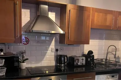 a kitchen with wooden cabinets and a stove top oven at Apartment with City Views - Sleeps 3 in Edinburgh