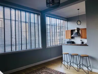 a kitchen with blue walls and stools and windows at Apartment with City Views - Sleeps 3 in Edinburgh
