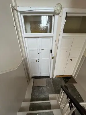 a staircase leading to a white door with a window at Dalblair Apartment in Ayr