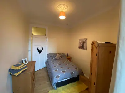 a bedroom with a bed and a desk and a lamp at Dalblair Apartment in Ayr