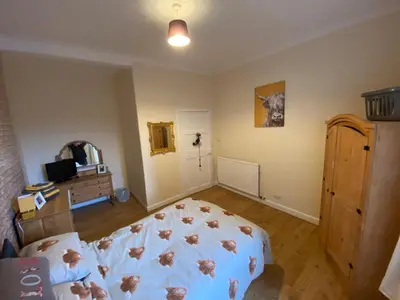 a bedroom with a bed and a dresser in it at Dalblair Apartment in Ayr