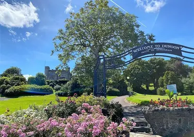 a welcome to dunedin sign in a park with flowers at Brookfield in Sandbank