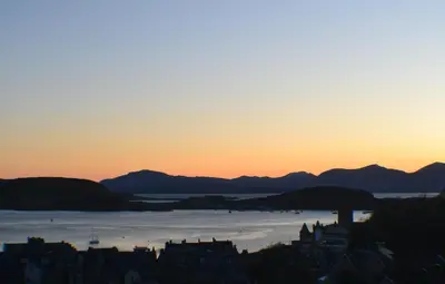 a sunset over a city with mountains in the background at Benvoulin Bothy - luxury pod with stunning views in Oban
