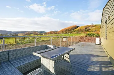 a hot tub on the deck of a house at Castlehill cabin with a hot tub in Peebles