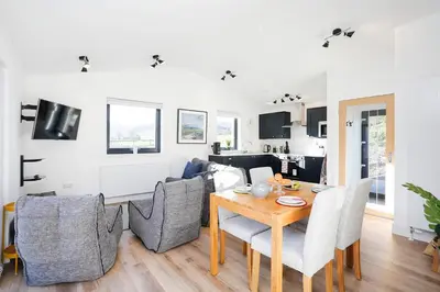 a dining room and living room with a table and chairs at Castlehill cabin with a hot tub in Peebles