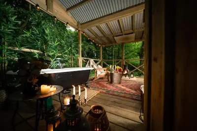 a bath tub sitting on a deck in a house at Cosy Cute Cabin with Large Veranda & Outdoor Bath in Glasgow