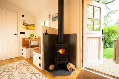 a living room with a fireplace in a house at Cosy Cute Cabin with Large Veranda & Outdoor Bath in Glasgow