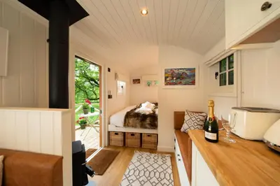a small room with a bed and a bottle of wine at Cosy Cute Cabin with Large Veranda & Outdoor Bath in Glasgow