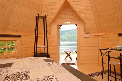 a bedroom with a bed in a log cabin at Seal Point Cabin - Luxury Glamping in Cairndow