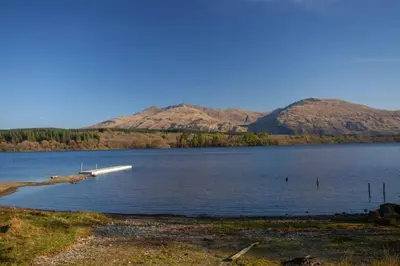 a boat on a lake with mountains in the background at New Build Lodge With Stunning Views of Loch Awe in Hayfield