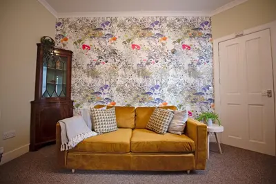 a yellow couch in a room with a floral wall at Cosy one bedroom flat in city center in Edinburgh