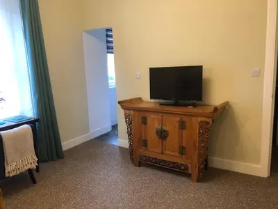 a flat screen tv sitting on a wooden stand in a room at Cosy one bedroom flat in city center in Edinburgh