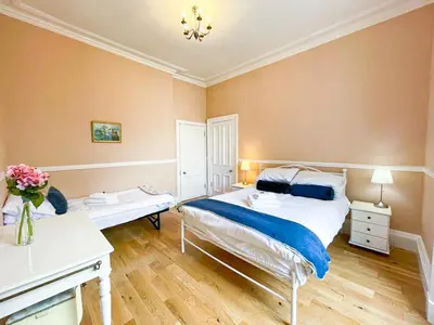 a bedroom with a bed and a vase of flowers at Remarkable 5BR Townhouse with Garden, Sleeps 12 in Edinburgh
