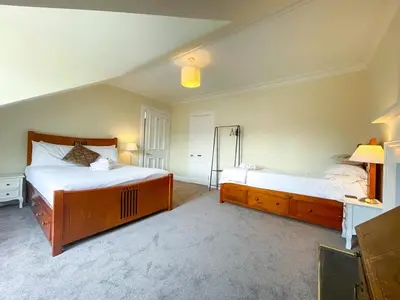 a large bedroom with two beds and a mirror at Remarkable 5BR Townhouse with Garden, Sleeps 12 in Edinburgh