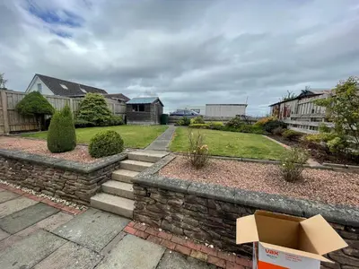 a house with a brick retaining wall and a yard at Viewlands house in Auchterarder