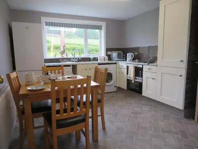 a kitchen with a table and chairs and a kitchen with a microwave at Marr Cottage in Thornhill