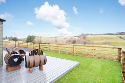two chairs sitting on a deck with a fence at Shiphorns luxury cabin with a hot tub in Eddleston