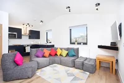 a living room with a gray couch with colorful pillows at Shiphorns luxury cabin with a hot tub in Eddleston