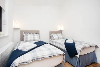two twin beds in a room with white walls at Shiphorns luxury cabin with a hot tub in Eddleston