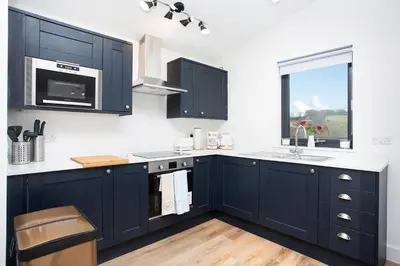 a kitchen with navy blue cabinets and a window at Shiphorns luxury cabin with a hot tub in Eddleston