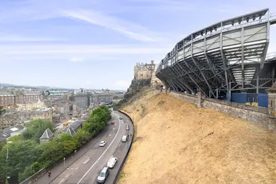 a stadium on top of a hill next to a road at JOIVY Cozy Apt near Edinburgh Castle in Edinburgh
