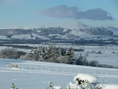 a snowy field with a fence and mountains in the background at St Michael's in Kippen