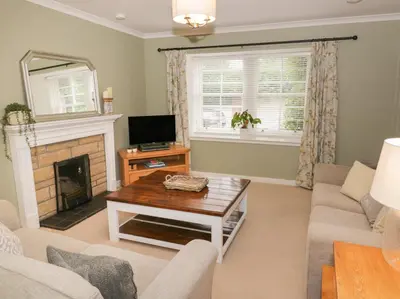 a living room with a couch and a fireplace at Greystones Cottage in Crieff