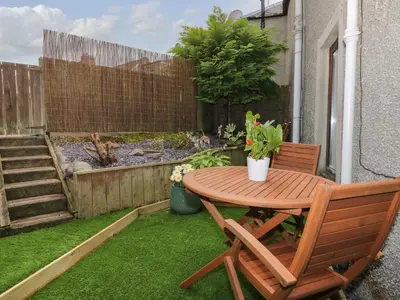 a wooden table and a chair on a small patio at Greystones Cottage in Crieff
