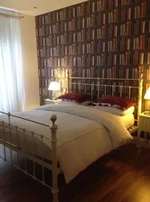 a bedroom with a large bed with a book wall at A Room in the City - West in Edinburgh